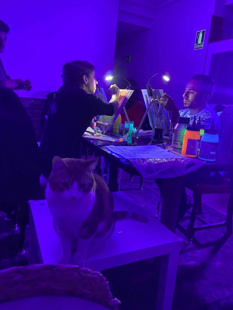Grupo pintando con pintura neón rodeado de gatos