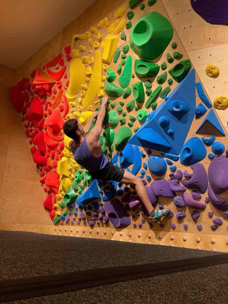 Persona escalando una parez arcoíris