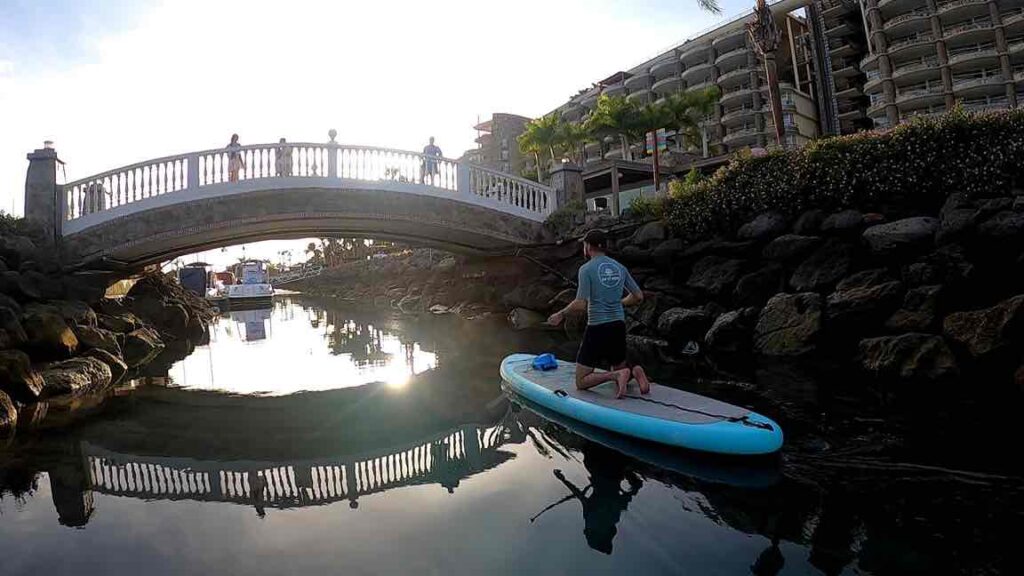 Chico pasando bajo un puente en tabla de Paddle Surf