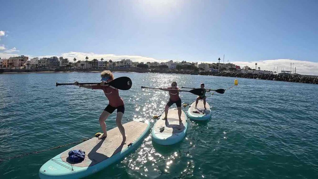 Sentadillas en tabla de SUP en clase de SUP Fit Yoga