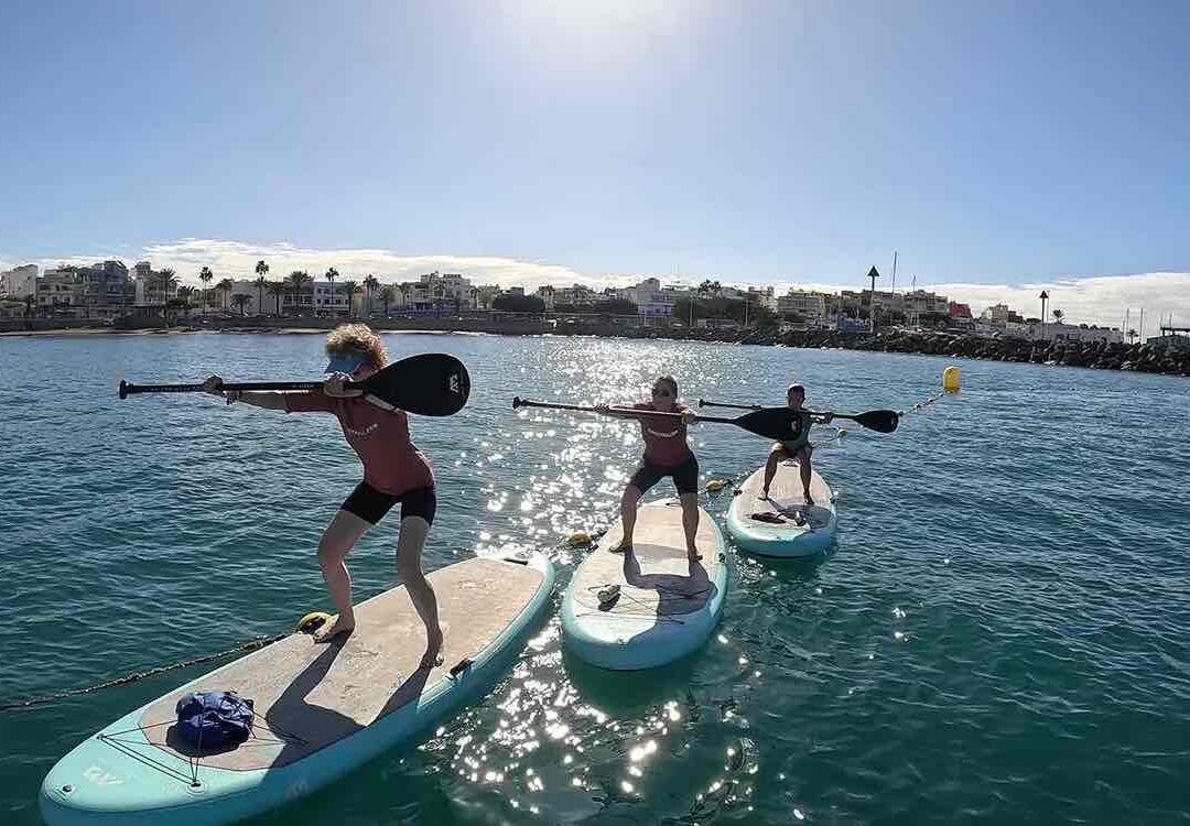 Sentadillas en tabla de SUP en clase de SUP Fit Yoga
